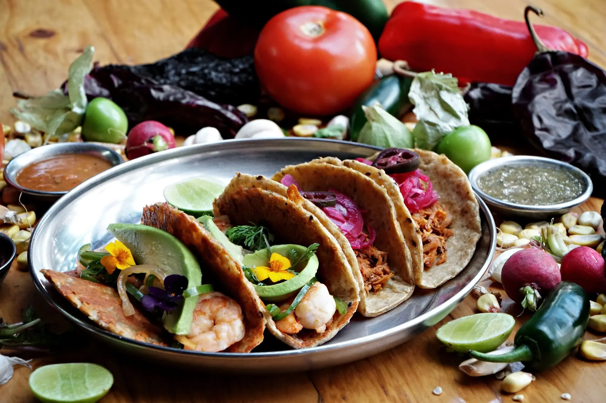 Tacos con cebolla morada, salsas, limones y chiles frescos
